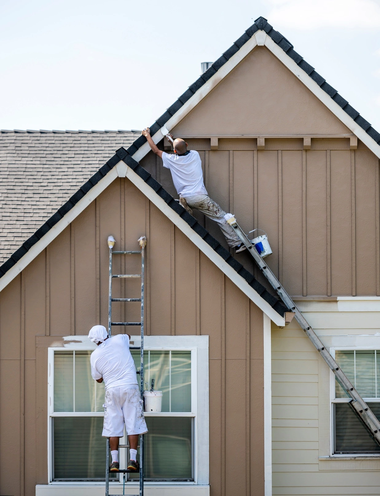 A man drilling shingles into a roof